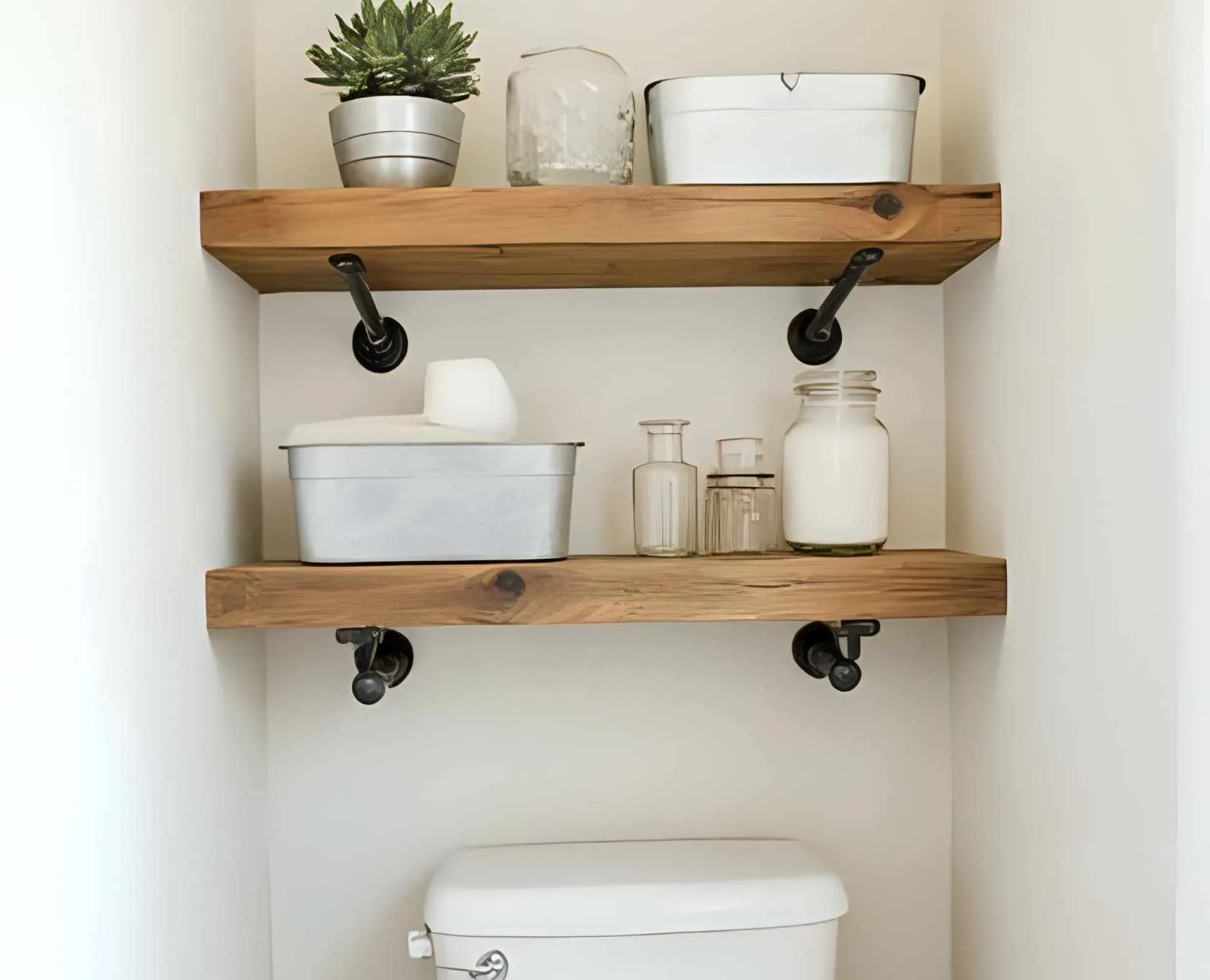 Black iron pipe brackets with reclaimed wood shelves above the toilet, for a modern rustic look.