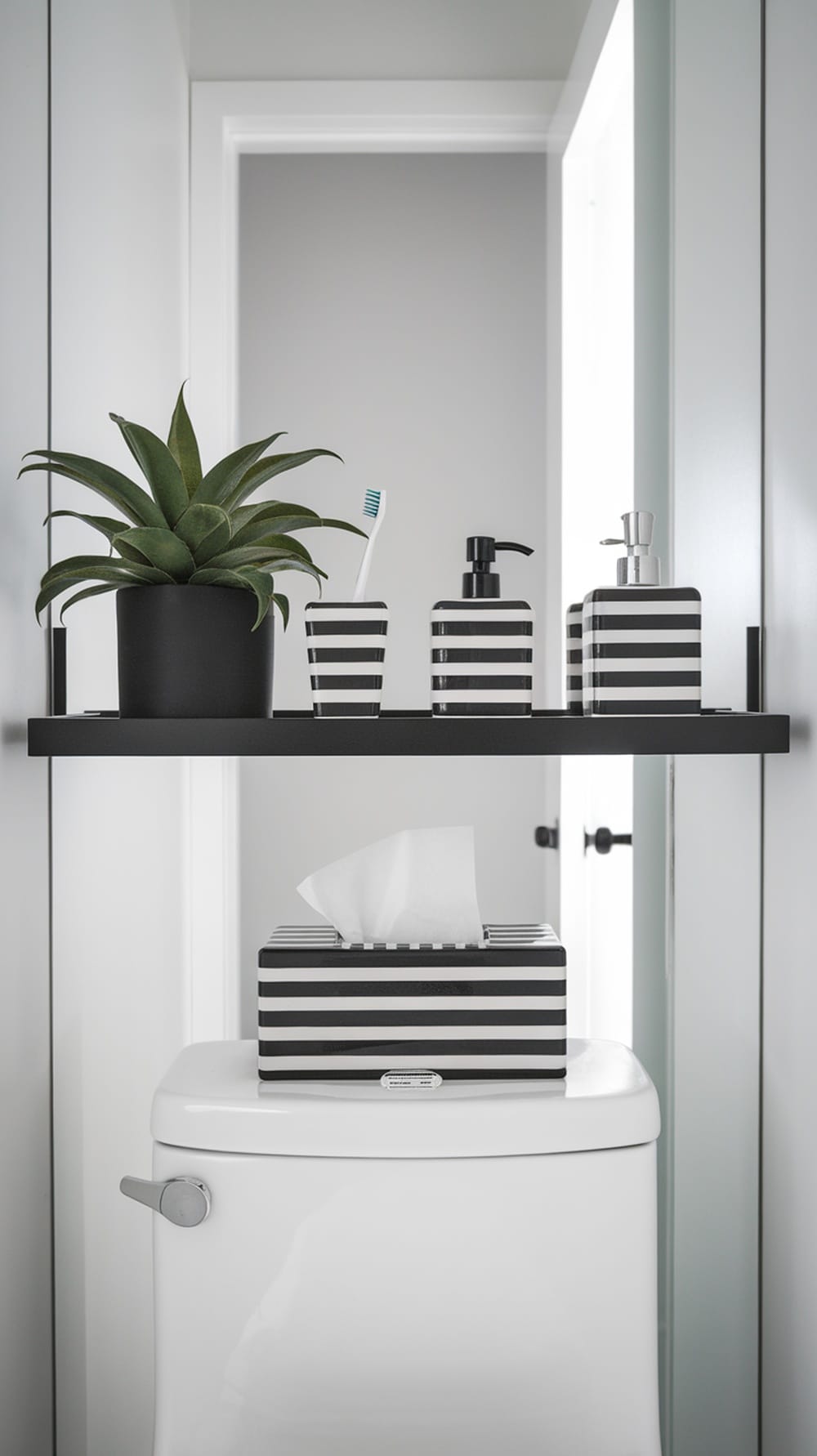 Modern black floating shelves with striped containers and a plant above a toilet.