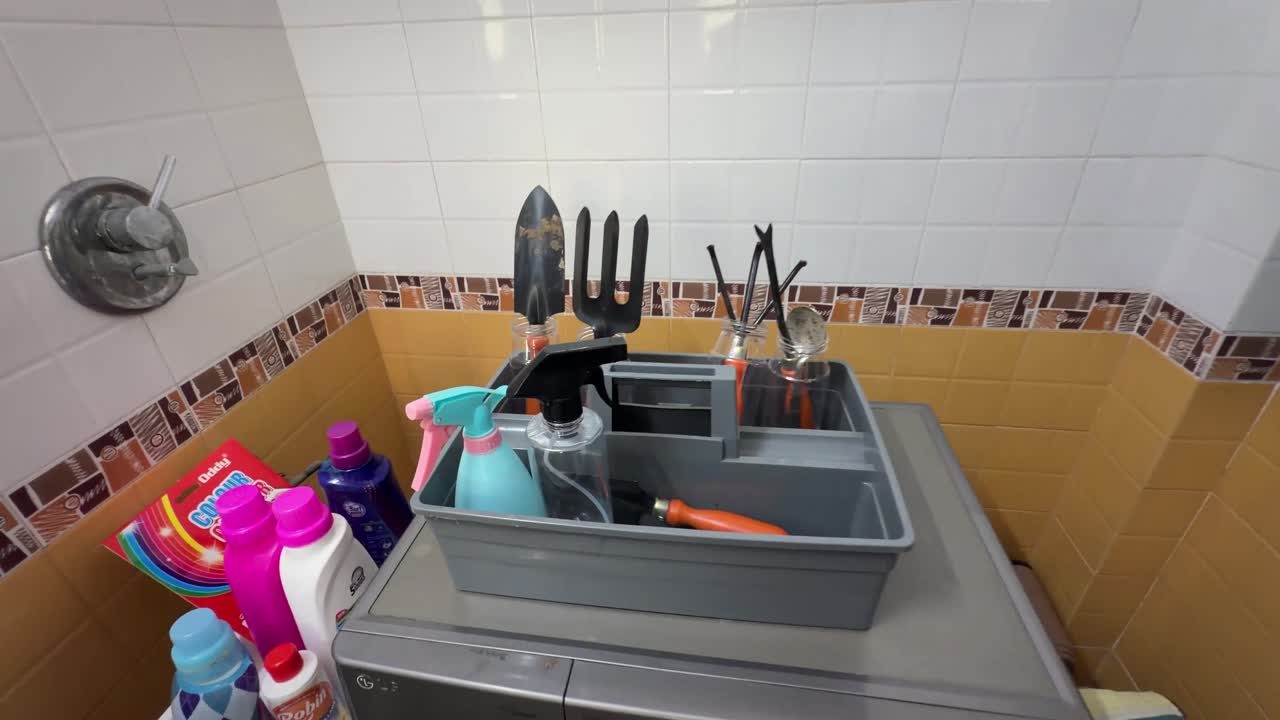 Repurposed grey caddy holding gardening tools and spray bottles in the laundry room
